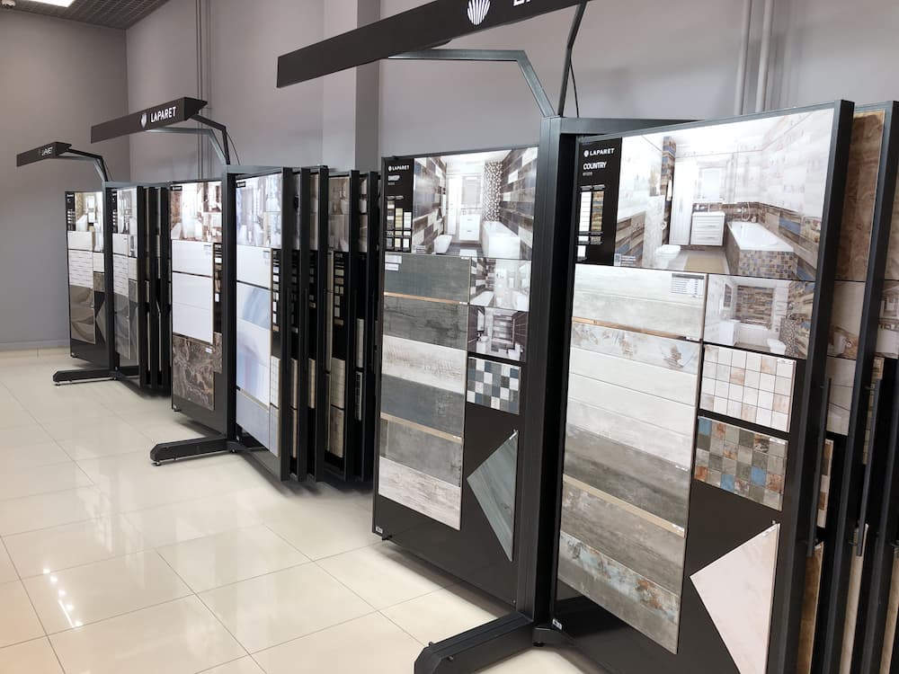 Expert hand arranging ceramic tiles on a table with samples and tools